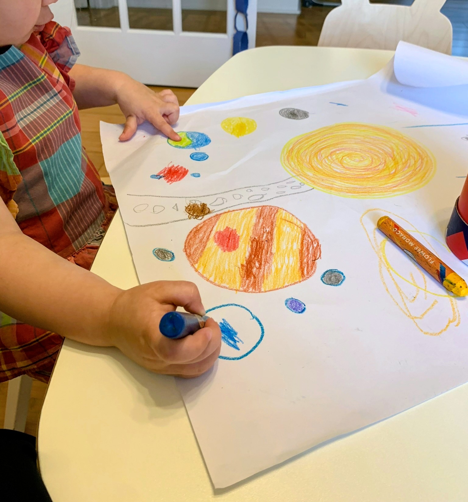 Child drawing the solar system with colorful crayons