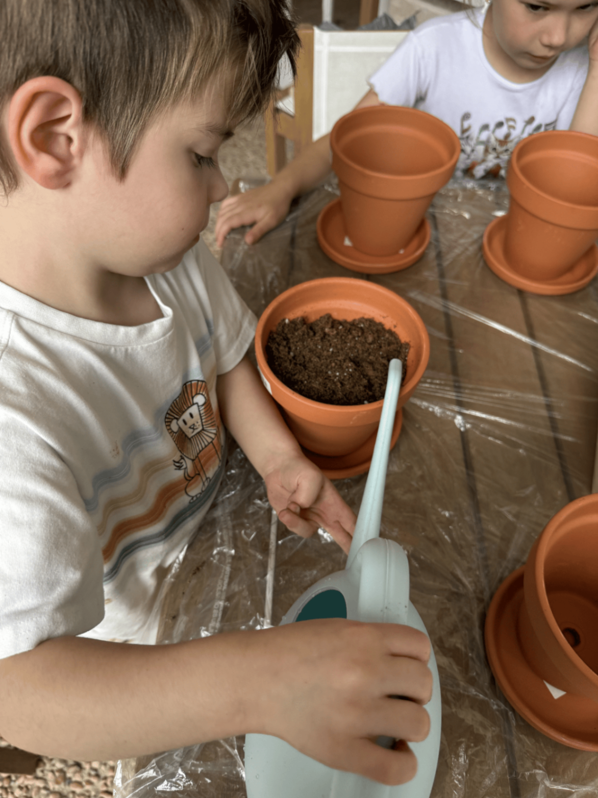 Child watering newly planted pots during a hands-on gardening activity